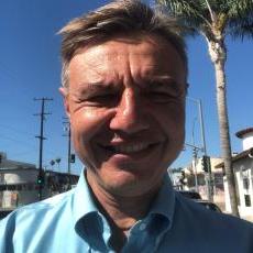 Alex smiling outside under a palm tree